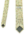 Amberwild Bloom - Cotton Tie with delicate orange and yellow blossoms on green foliage against a pale background
