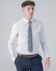 Man wearing a white shirt and navy trousers featuring a green floral patterned cotton tie from Clover Grove collection.