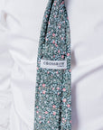 Close-up of Clover Grove cotton tie with floral pattern in green, red, and white worn over a white dress shirt.