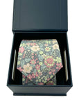 Floral cotton tie in blush, peach, sage, and ivory on charcoal, presented in a black gift box for special occasions.
