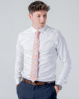 Man wearing white shirt and navy pants with a floral patterned Cotswold Bloom - Tie against a plain background