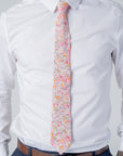 Cotswold Bloom - Tie featuring a floral pattern in pink, orange, and yellow on a beige background worn with white shirt.
