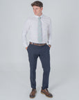 Man wearing a William Morris Golden Lily Sage cotton tie with white shirt, navy pants, and brown shoes on plain background