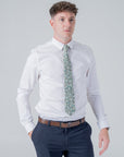 Man wearing Elmwood Bloom cotton tie with white floral pattern paired with white shirt and navy pants