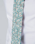 Close-up of a cotton tie with a delicate white and brown floral pattern on a forest green background.