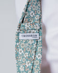Close-up of Elmwood Bloom cotton tie in forest green with white and brown floral pattern and Crossrow London label