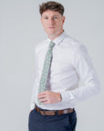 Man wearing Elmwood Bloom cotton tie with floral pattern paired with white shirt and navy trousers