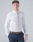 Man wearing Amberwild Bloom Cotton Tie with orange and yellow floral pattern paired with white shirt and navy pants