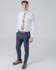 Man wearing Camden Block Check Tie with ochre, rust, sage, and blue hues paired with white shirt and navy trousers
