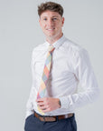Man wearing white shirt and colorful Camden Block Check tie with ochre, rust, sage, and blue patchwork design