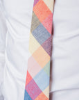 Close-up of Camden Block cotton tie with vibrant patchwork of ochre, rust, sage, and blue hues on a white shirt.