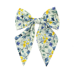 Blue Blossoms girls' cotton bow tie with a floral design of blue and yellow flowers on a soft green ground.
