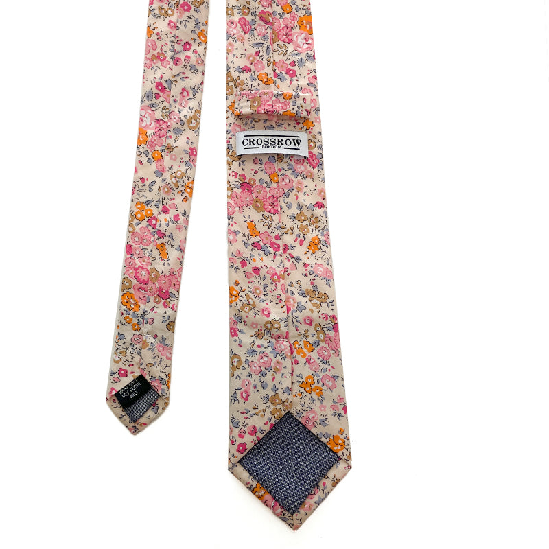 Cotswold Bloom tie with a vibrant floral pattern in pink, orange, and yellow on a beige background