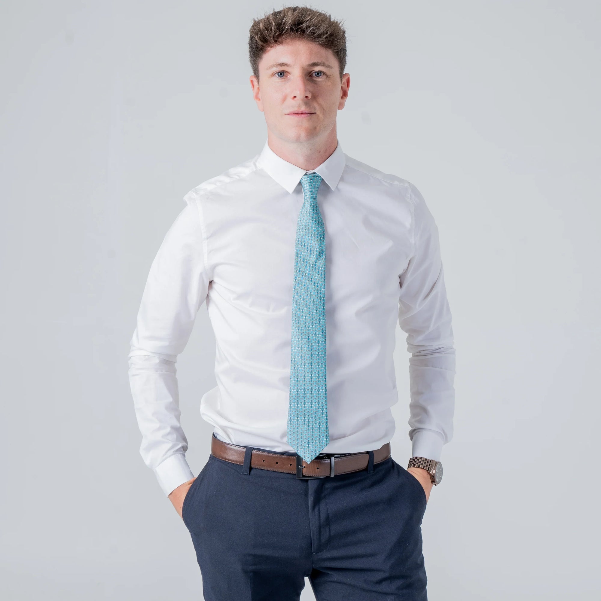 Man wearing Dragonfly Dance - Silk Tie in teal with dragonfly pattern paired with white shirt and navy pants