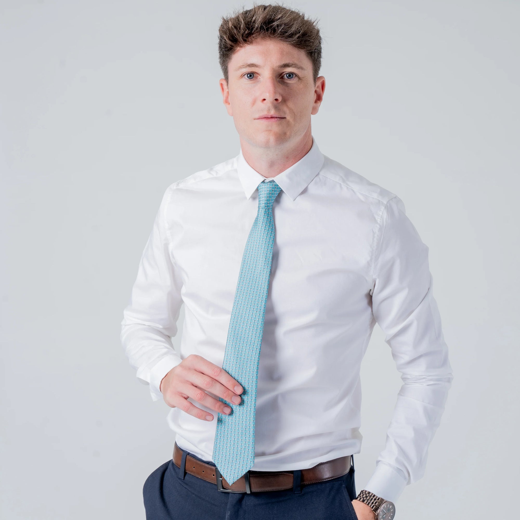 Man wearing white shirt and Dragonfly Dance - Silk Tie with teal dragonfly pattern standing against plain background