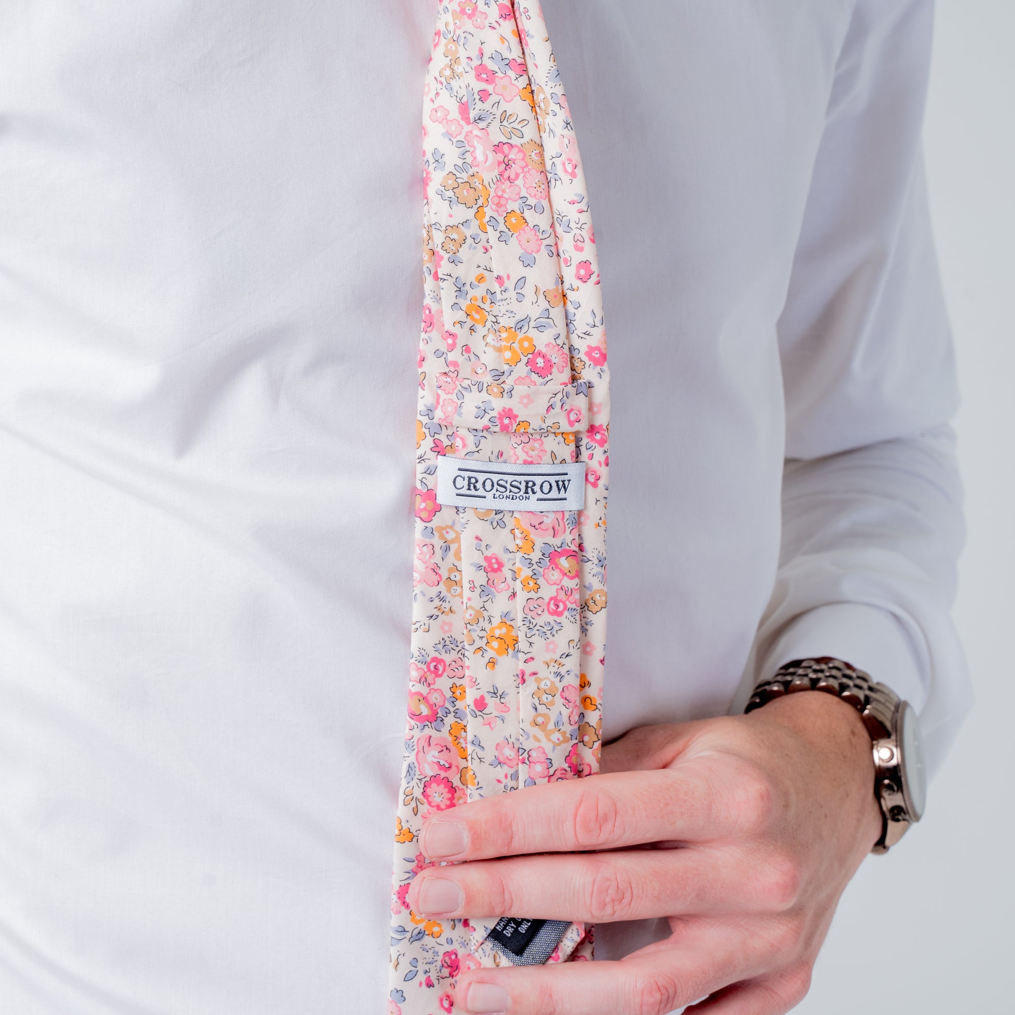 Cotswold Bloom - Tie featuring a floral pattern in pink, orange, and yellow on a beige background.